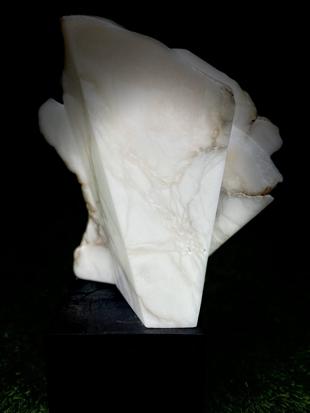 A sculpture in white Alabaster, mounted on a black oak block. Slices are cut through the stone to create an abstract fan shaped object.